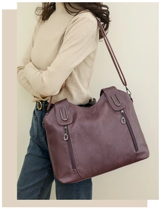 Detail view of the purple leather tote bag with metallic hardware on a model outdoors