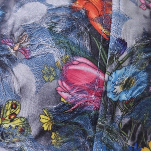 Macro detail of denim baseball cap with floral print and distressed fringe texture