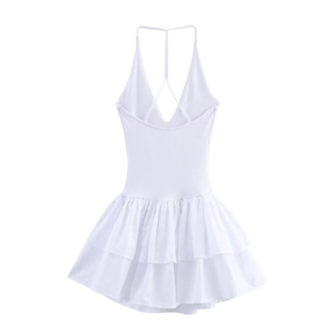 Detail of white halter dress featuring cross-back straps and tiered ruffle skirt