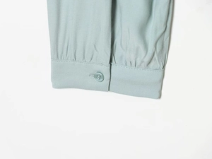 Close-up of light green blouse cuff showing button detail and high-quality woven fabric