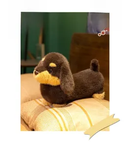 Détail d'une peluche teckel marron foncé et beige sur un oreiller rayé