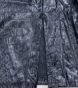 Dettaglio del vestito nero in pelle di coccodrillo con texture raffinata e spacco laterale