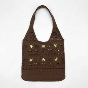 Detail view of dark brown crochet shoulder bag with 3D white floral embroidery and green leaves