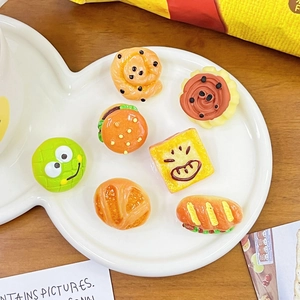 Detailed view of realistic miniature resin hamburger and bread charms on a white fish plate