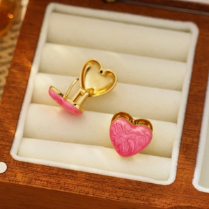 Boucles d'oreilles cœur en marbre rose et monture dorée sur velours blanc luxueux