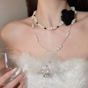 Detail of elegant double-layer pearl necklace with a vintage black knit flower ornament