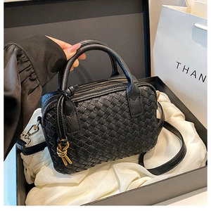 Detail of black hand-woven leather Boston bag with gold hardware and knotted zipper pull