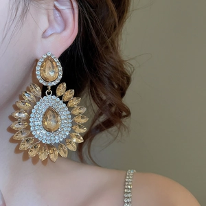 Close-up of champagne crystal teardrop flower earrings on a model in warm light