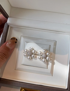 Gros plan de boucles d'oreilles fleurs en perles avec centre en zircon dans un écrin