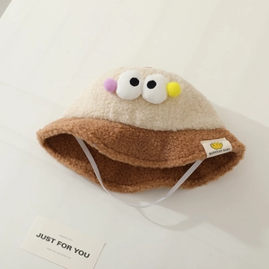 Detailed macro view of soft off-white lamb wool baby bucket hat with cartoon eye accents