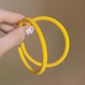 Detailed view of large matte yellow acrylic hoop earrings held for style display