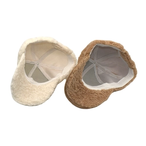 Detail view showing soft plush faux shearling texture on baseball caps in beige and brown