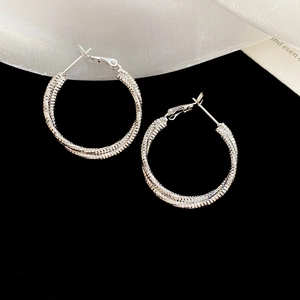 Macro shot of silver round hoop earrings with detailed woven texture and metal layers