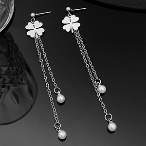 Detailed close-up of long tassel earrings with clover motif and dangling pearls
