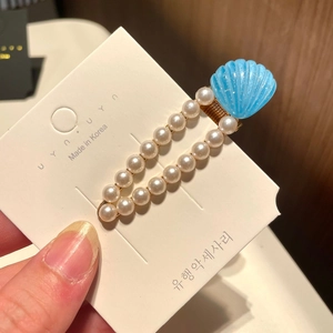 Close-up of blue glitter shell hair clip with cream pearls and gold metal clip