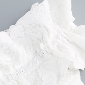 Close-up of white floral lace embroidery and elastic smocked details on summer dress