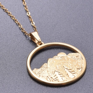 Close-up of gold 18k plated necklace featuring a circular mountain and sun relief pendant
