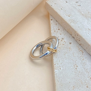 Detail of linked silver and gold rings with polished finish on beige stone