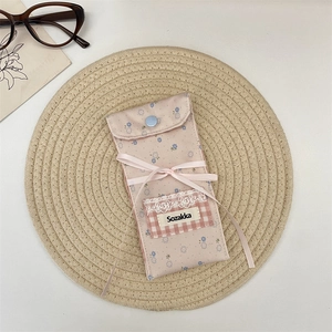 Floral fabric eyewear pouch detail with blue snap button and ribbon bow accent