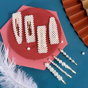 Detail of 8-piece gold metal hair clip set with white pearls in geometric shapes