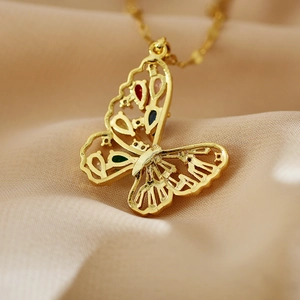 Vue macro d'un pendentif papillon doré avec des zircons colorés et un design évidé