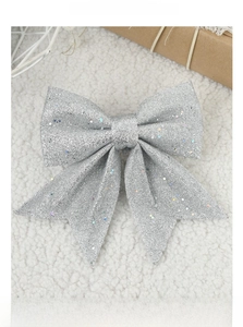 Sparkling silver glitter bow decoration on soft white plush background for Christmas