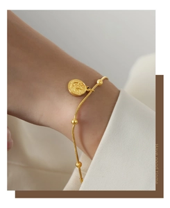 Detail of gold-plated snake chain bracelet with coin pendant and portrait engraving