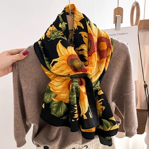 Sunflower print silk scarf on black background styled with a warm brown knit sweater