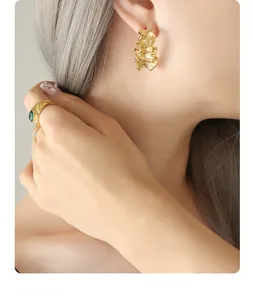 Vue rapprochée de boucles d'oreilles dorées à texture froissée irrégulière