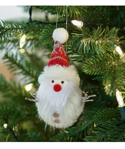 Close-up of plush Santa Claus ornament with red knit hat on a lighted Christmas tree