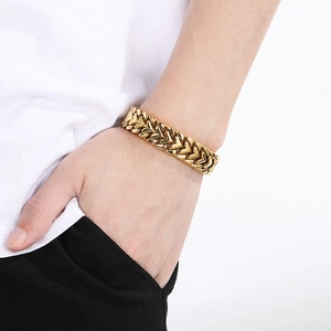 Close-up of men's wide golden V-weave chain bracelet showing intricate metal texture