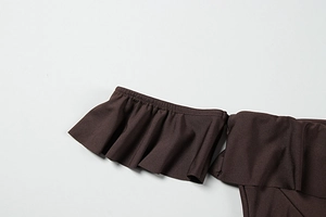 Detail of dark brown ruffle stitching and high-quality textured fabric on the dress