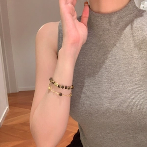 Detail of 18K gold-plated beaded bracelet set with tiger eye stones on model's wrist