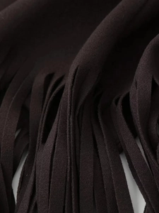 Detailed close-up of dark fringe tassels and premium woven texture on a fashion jacket
