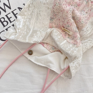 Detail of canvas tote bag showing lace trim, floral patterns, and magnetic closure