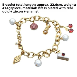 Detailed view of the gold-plated charm bracelet with cherry, pearl, and enamel accents
