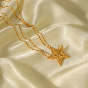 Detailed shot of golden star pendant with textured surface on elegant beige silk fabric