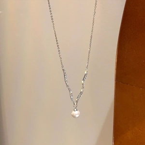 Detail of silver V-shaped necklace pendant with white pearl and sparkling zircons