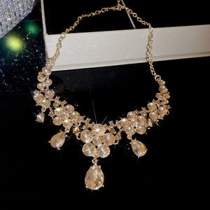 Detailed view of the gold flower necklace with teardrop pendants on a black surface