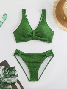 Detailed flat lay of green smocked texture bikini set with stylish summer holiday accessories