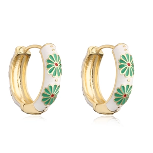 Detailed macro of gold-plated hoop earrings with white enamel and floral patterns
