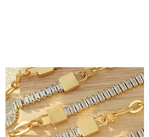 Détail de chaîne plaquée or 18K avec zircons géométriques sur fond de bois clair