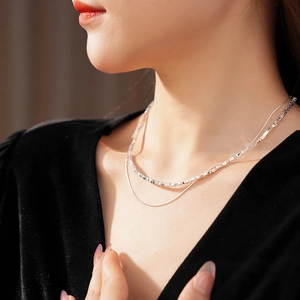 Close-up of double layer silver necklace with fine and box chains on black V-neck top
