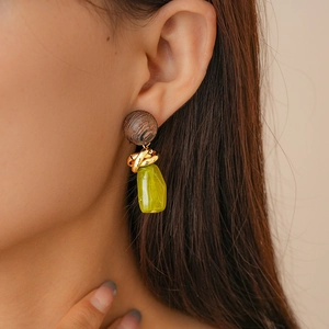 Detail of vintage resin earring with wood grain top, gold metal twist and green pendant
