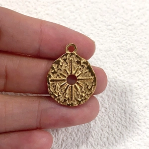Close-up of golden stainless steel sunburst charm with textured surface for DIY jewelry