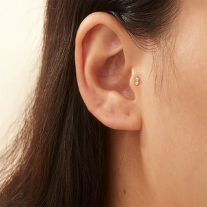 Close-up of a 16G gold diamond geometric ear stud worn on the tragus for a trendy look
