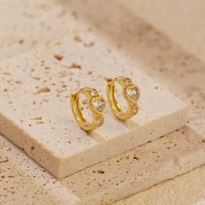 Macro detail of gold-plated silver hoop earrings with heart-shaped sparkling crystals
