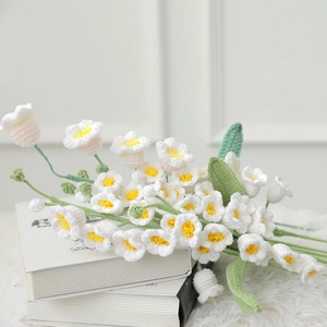 Detail of handmade crochet Lily of the Valley bouquet on white books for decor