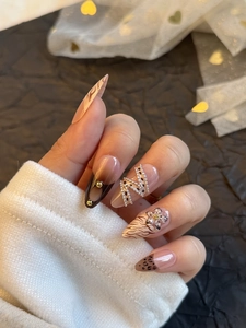Close-up of stiletto nails featuring leopard print, 3D floral carving and gold chain charms