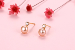 Close-up of pink freshwater pearl earrings with zircon inlay on a floral pink background